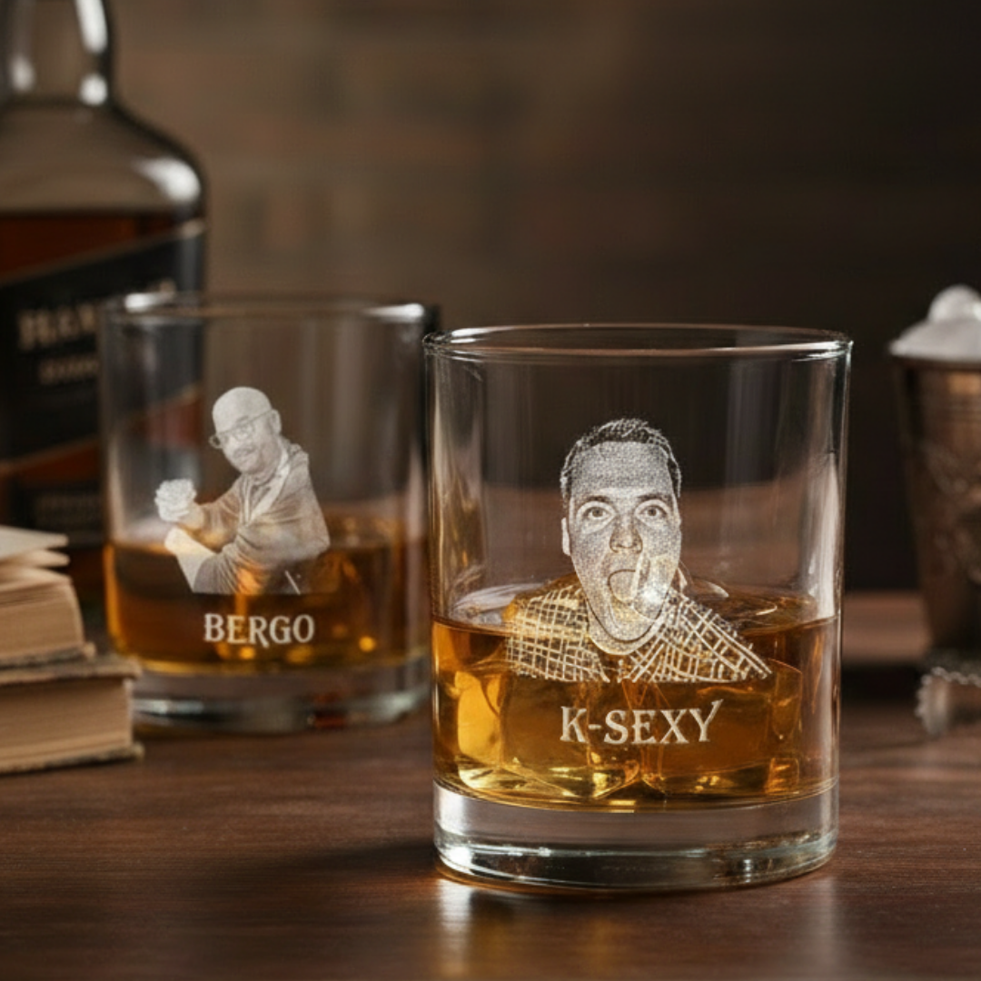 Whiskey glass filled with amber liquid, laser-engraved with sample portrait labeled "K-SEXY" and crosshatch pattern, displayed alongside matching glass engraved with "BERGO