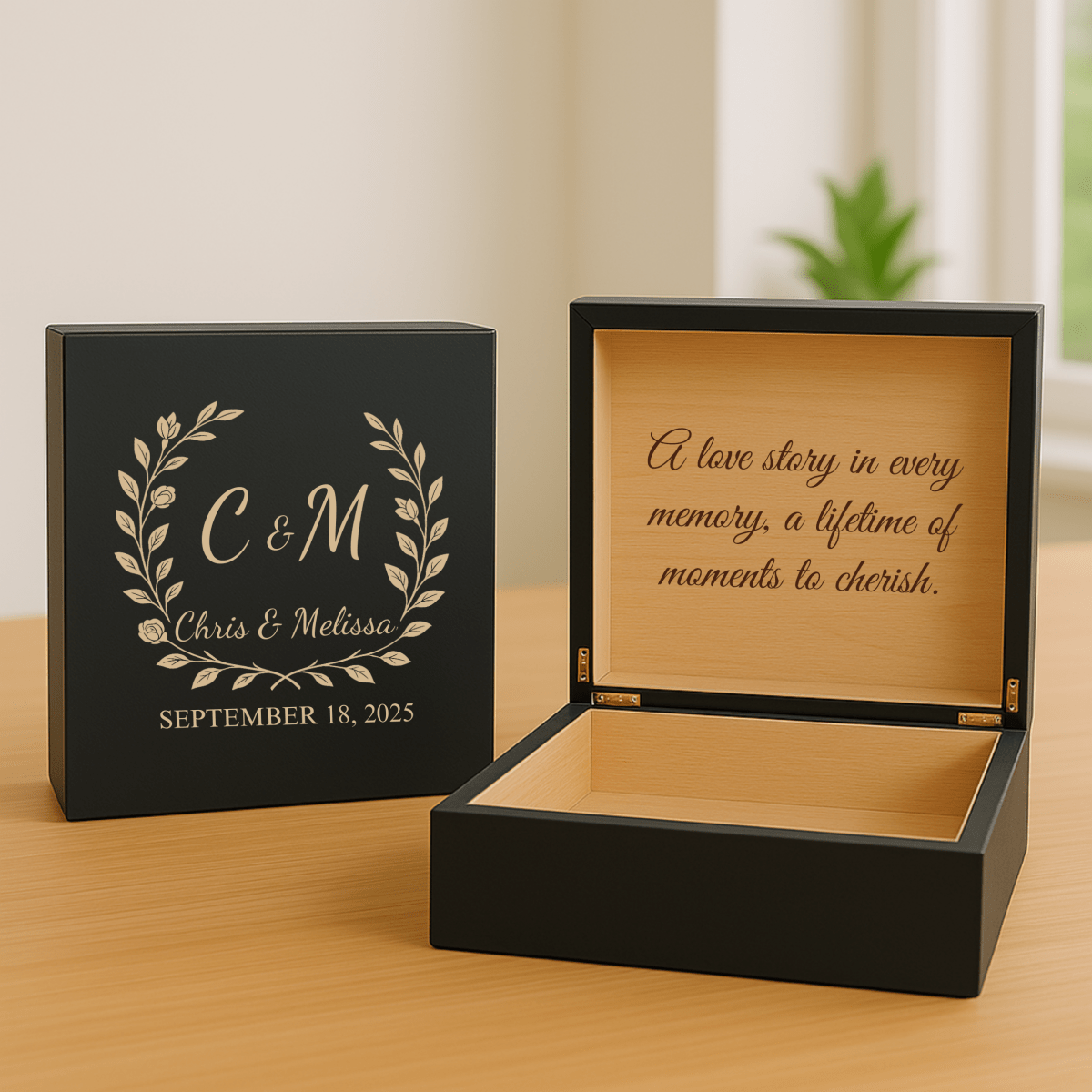 Black keepsake box with engraved monogram "C & M" and laurel wreath on lid, open to show interior engraved with sample message "A love story in every memory, a lifetime of moments to cherish" and maple wood interior.