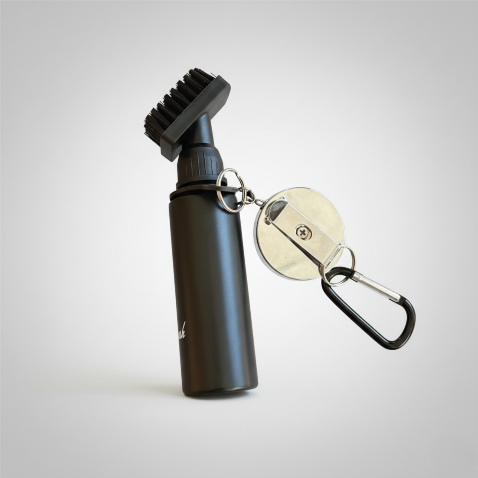 Black golf ball cleaner brush with attached metal ball marker featuring sample star engraving and carabiner clip
