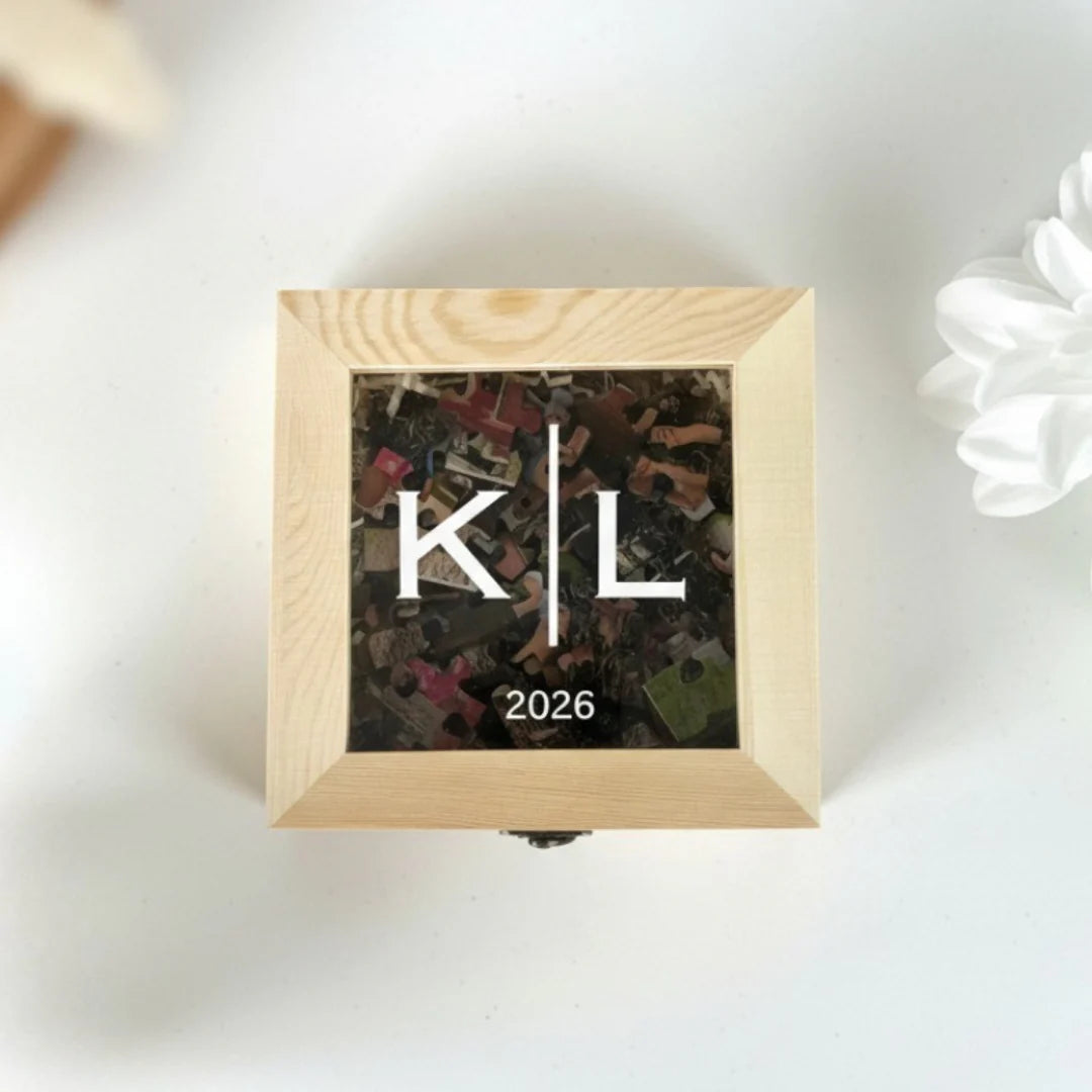 Natural wood keepsake box with window display showing customized photo puzzle featuring sample initials "K" and "L" with date "2026" engraved on cover