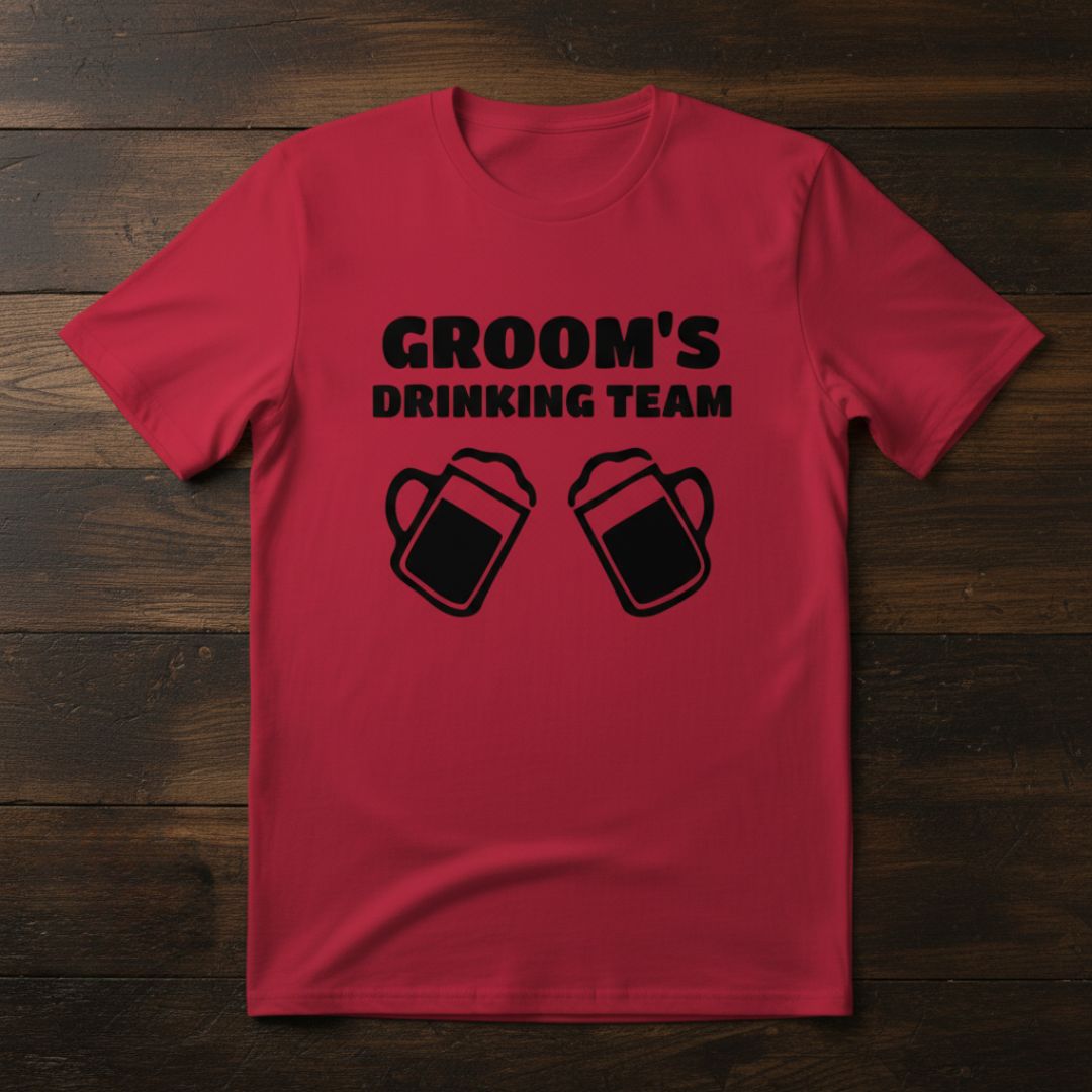 Red t-shirt printed with black text reading "GROOM'S DRINKING TEAM" and two beer mug graphics below the text