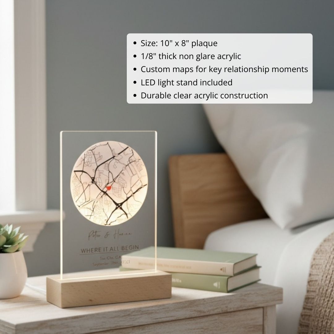 Clear acrylic map plaque with LED light stand displaying customized circular map with sample text "Peter & Maria" and "WHERE IT ALL BEGIN" on wooden base.
