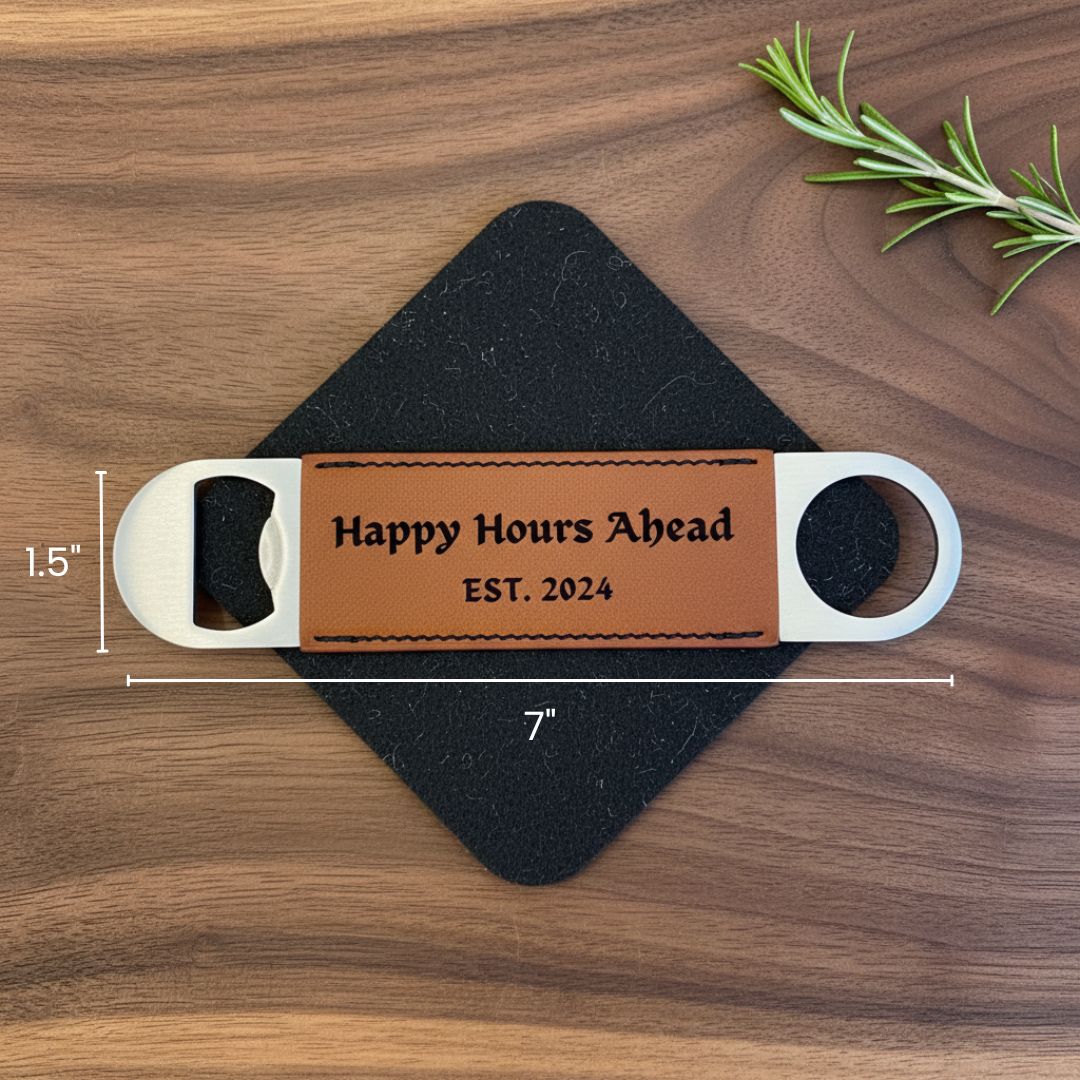 Tan leather bottle opener with white metal handles engraved with sample text "Happy Hours Ahead" and "EST. 2024" displayed on dark felt surface with dimensions marked as 7" long and 1.5" tall