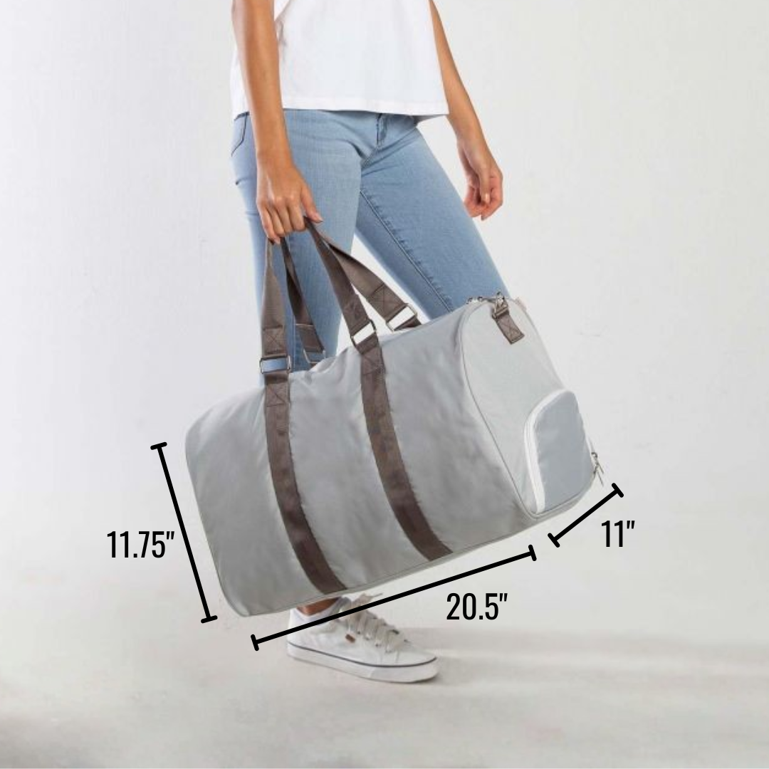 Light gray duffle bag with brown handles and trim, shown held by person wearing white shirt and jeans, with dimensions labeled 20.5" x 11" x 11.75