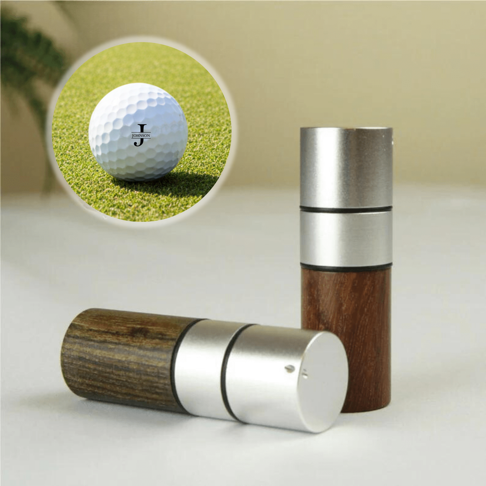 Wooden golf ball stamp shown in three color variants with brushed metal and wood construction, featuring inset detail of personalized golf ball marked with sample monogram on green turf