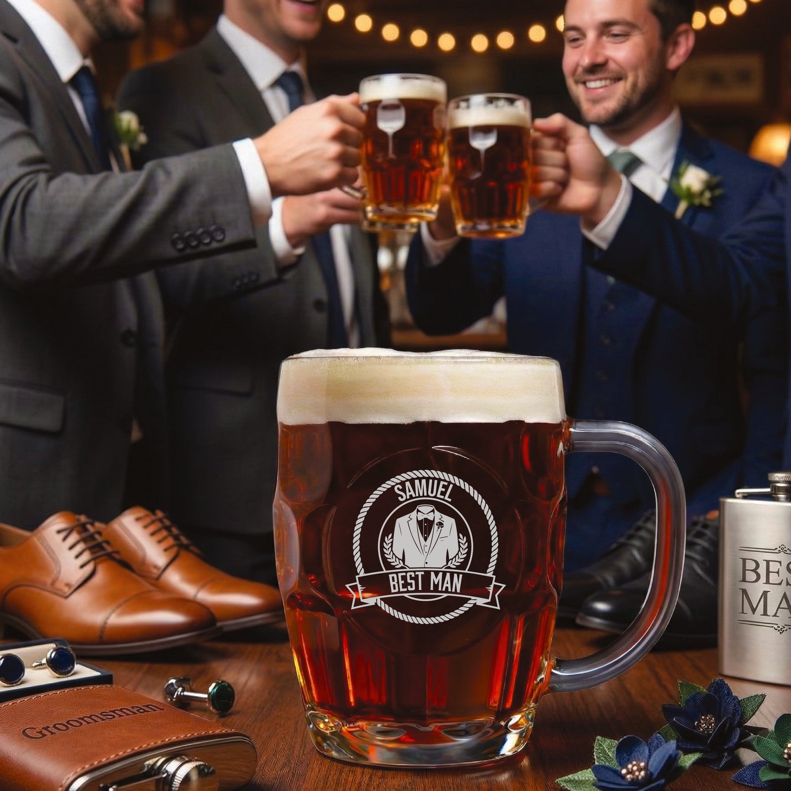 Beer mug engraved with sample personalization "Samuel Best Man" featuring tuxedo and laurel wreath design, filled with beer and displayed among groomsmen toasting in background