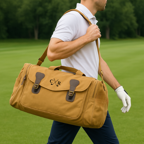 Tan canvas duffle bag with leather trim, worn over shoulder by man in white polo, showing personalized monogram "CXR" and crossed golf clubs embroidery on front flap