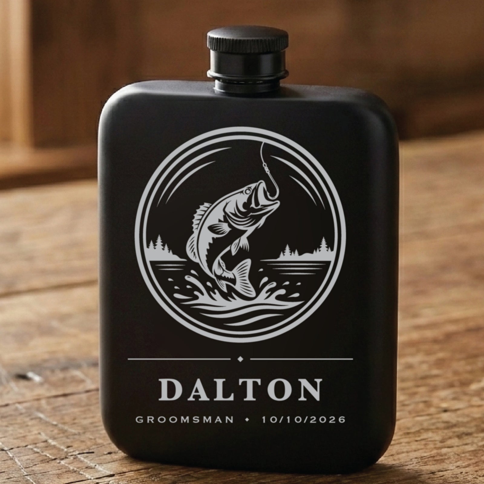 Matte black fishing groomsmen flask laser engraved with a leaping bass above the name Dalton, his role and the wedding date.