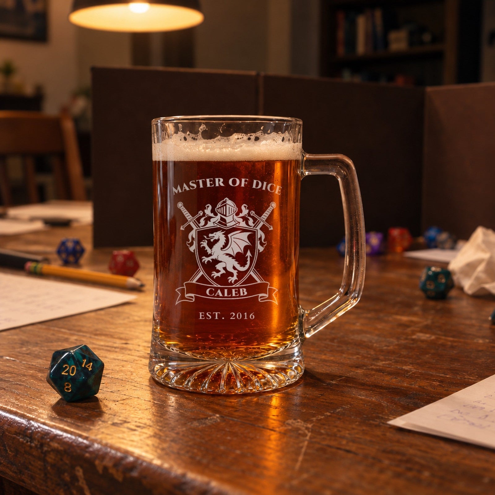 Personalized dragon crest beer mug on a game night table beside dice and a game screen, engraved MASTER OF DICE, CALEB and EST. 2016, a gift for the groomsman who runs the campaign