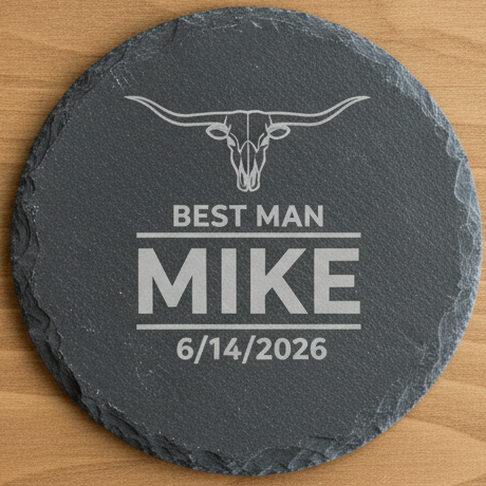 Close detail of a single personalized slate coaster engraved with a longhorn emblem, wedding role, first name, and wedding date