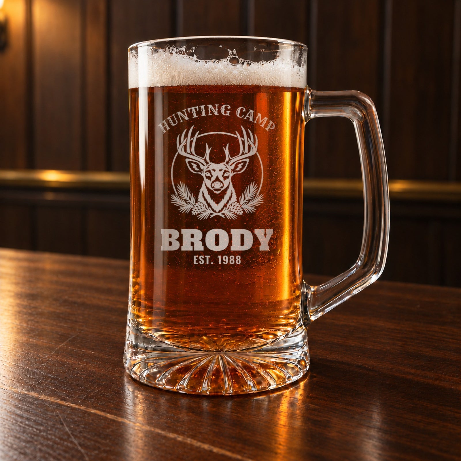 Personalized hunting camp beer stein on a walnut bar, engraved with a whitetail buck and pine boughs: Hunting Camp, Brody, Est. 1988