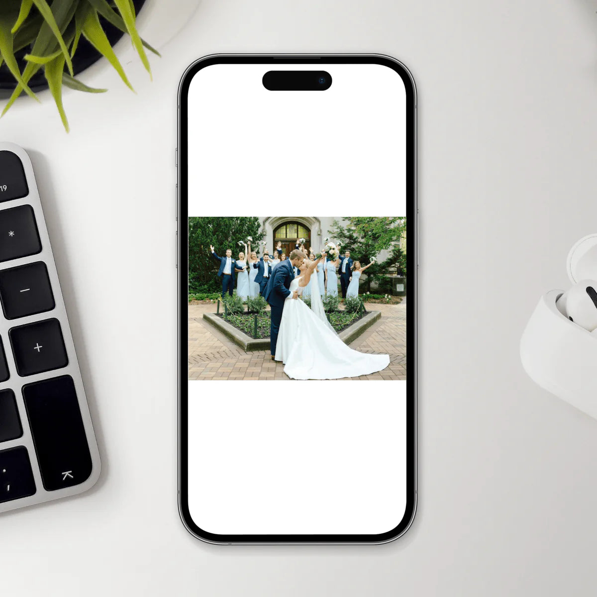 Smartphone displaying sample wedding photo on puzzle keepsake mockup, showing bride and groom with wedding party on brick patio