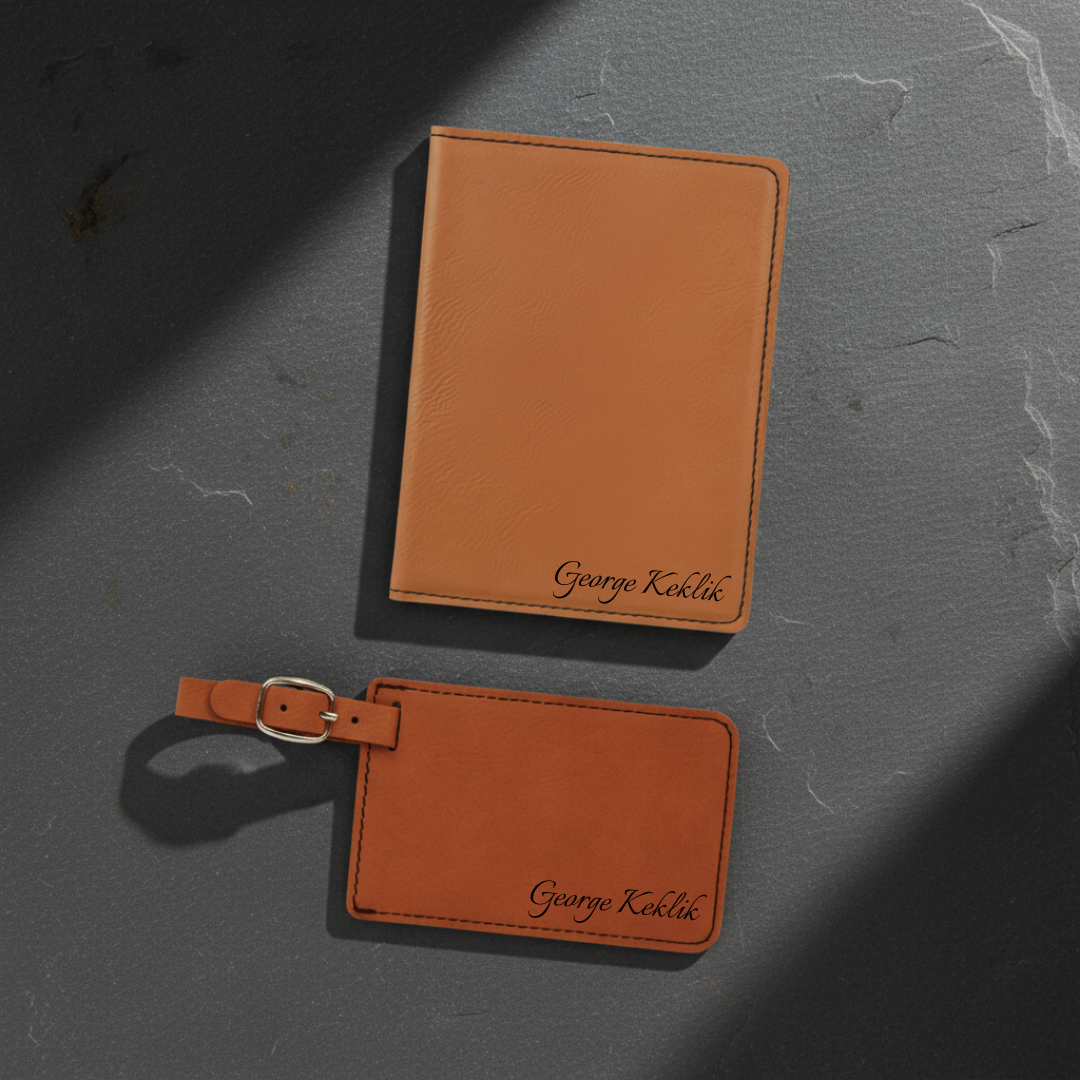 Light brown passport cover and rawhide luggage tag on dark slate, each engraved George Keklik in black script in the lower right corner
