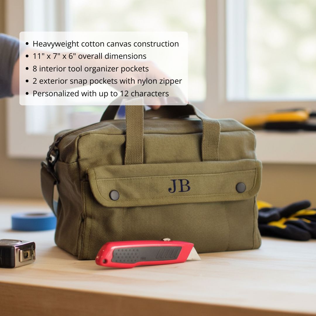 Tan canvas tool tote with monogrammed initials "JB" on front flap pocket, displayed on workbench with tools and supplies
