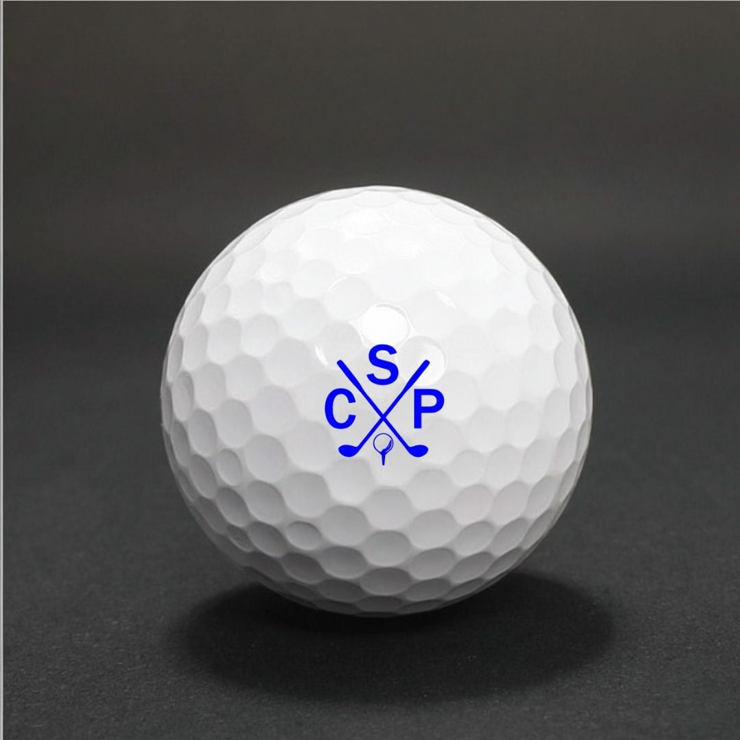 White golf ball with dimpled surface, printed with sample blue monogram design featuring crossed golf clubs and initials "CSP