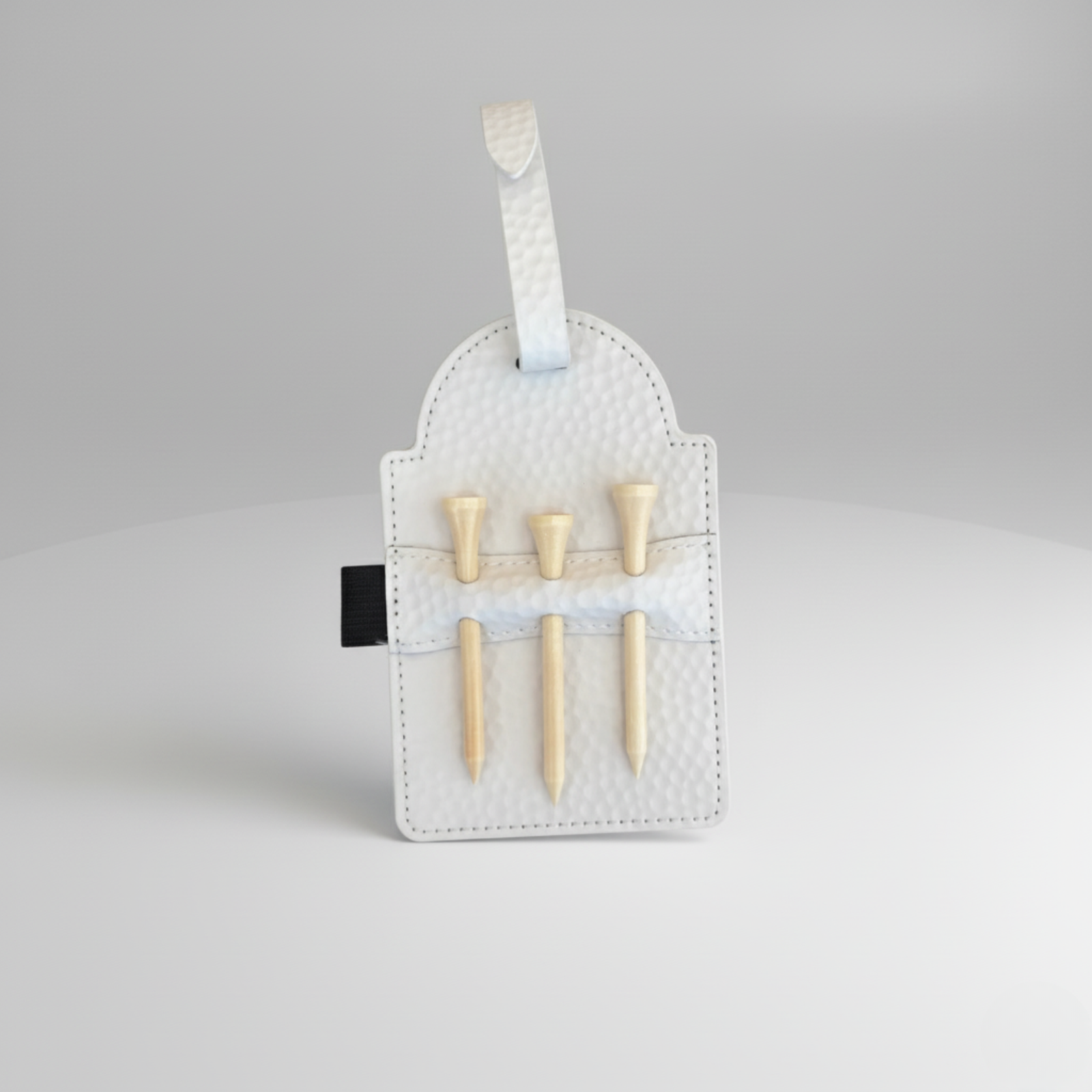 White quilted golf accessory pouch with six wooden golf tees displayed in elastic slots and a white ribbon handle