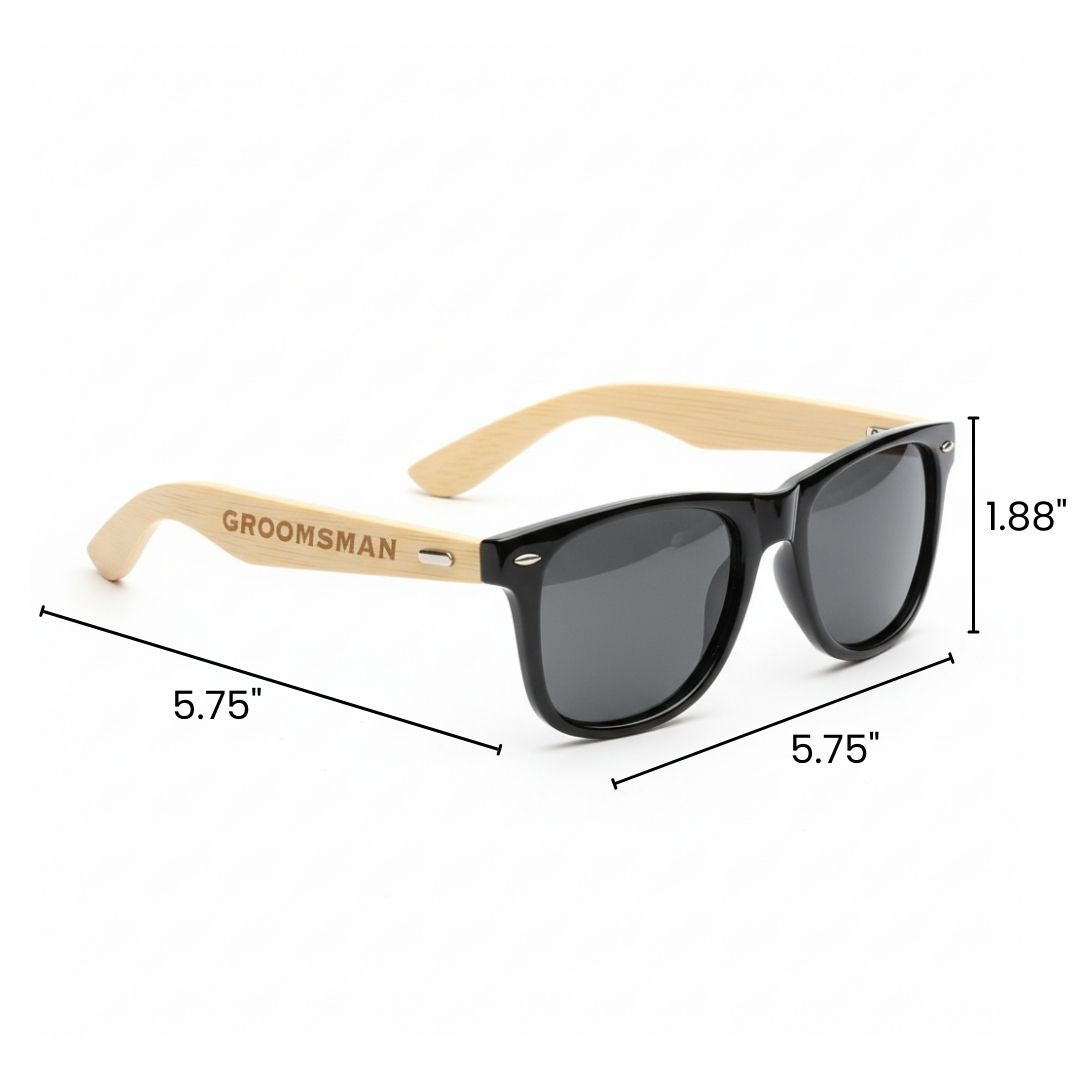 Black sunglasses with natural wood grain arms engraved with sample text "GROOMSMAN" in tan wood finish, shown with dimensions.