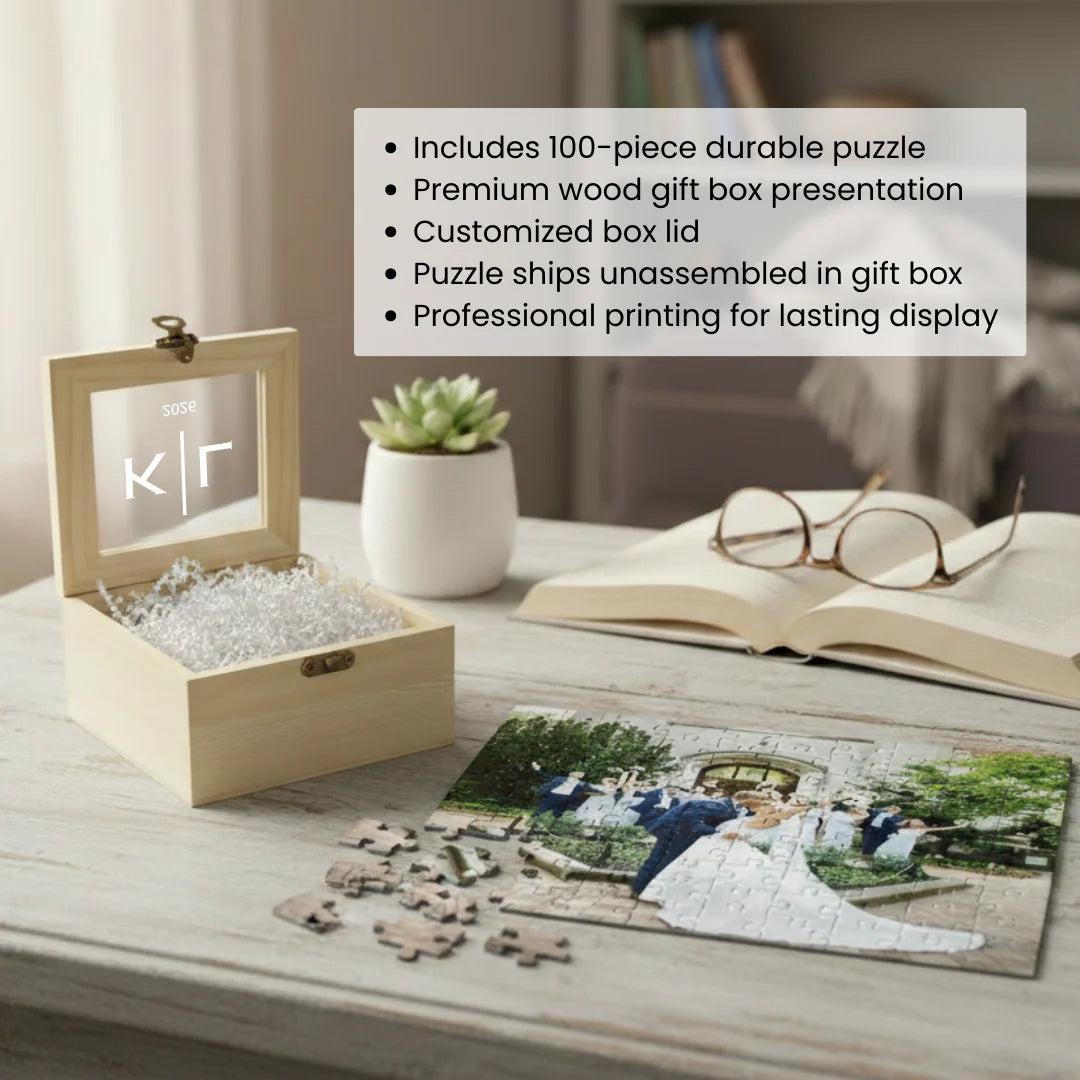 Natural wood box with personalized lid showing sample initials "K|F" and "50SE" text, filled with puzzle pieces and displaying an assembled custom photo puzzle on the desk below