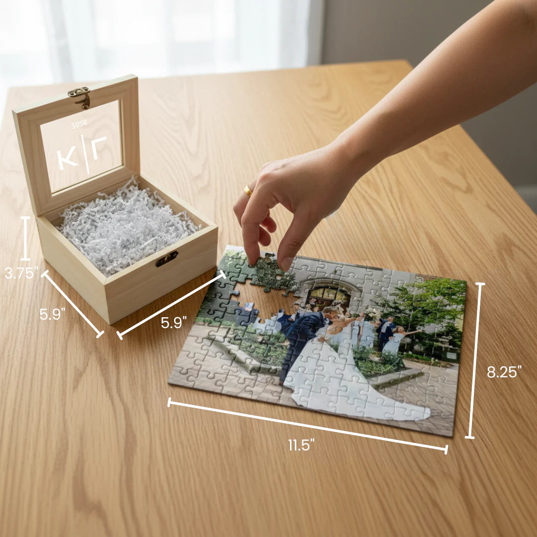 Natural wood box with engraved sample initials "KJF" and shredded paper interior, displayed alongside custom photo puzzle showing wedding scene with couple and guests