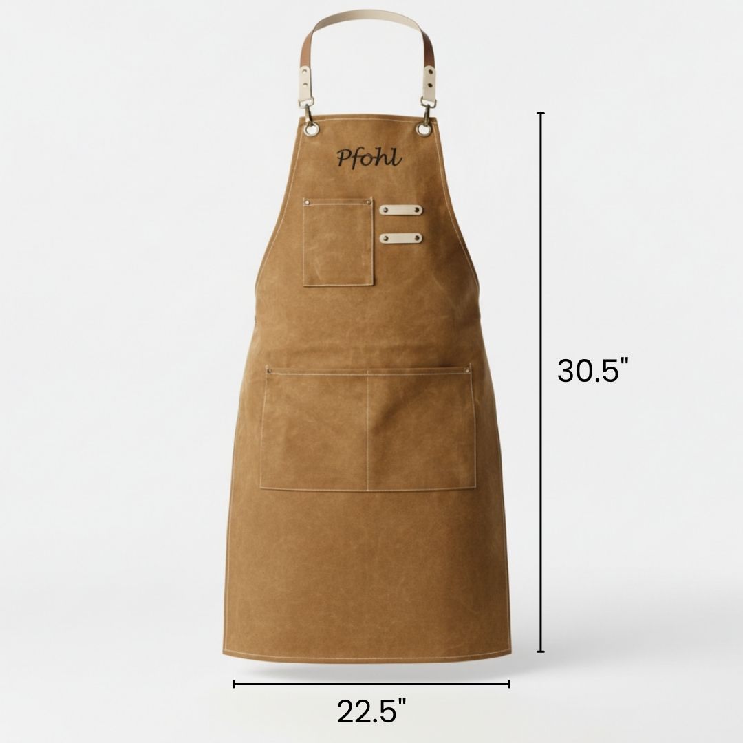 Tan waxed canvas apron with personalized "Pfohl" engraving, dual front pockets, leather straps, and dimensions marked 30.5" height by 22.5" width
