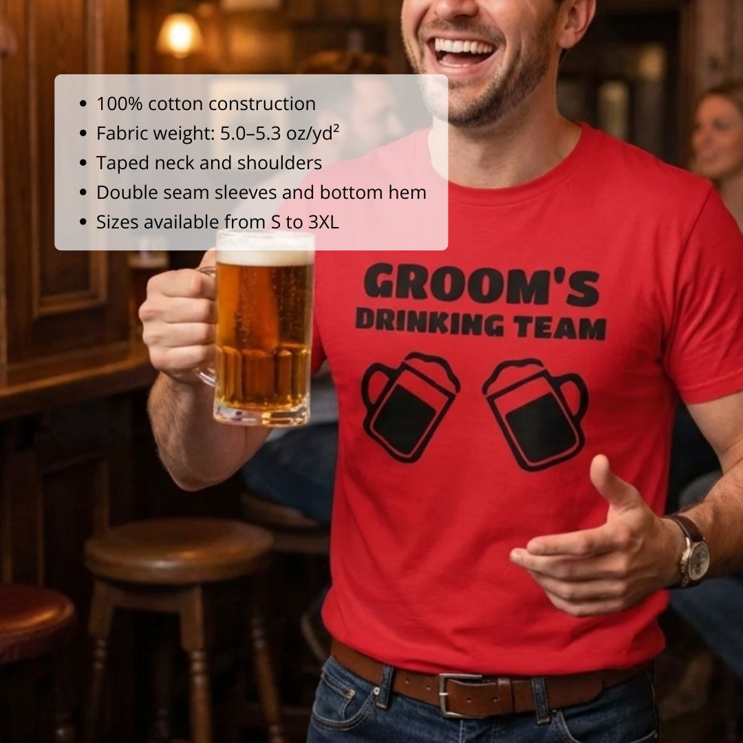 Man wearing red t-shirt with "GROOM'S DRINKING TEAM" text and beer mug graphics, holding beer glass in bar setting