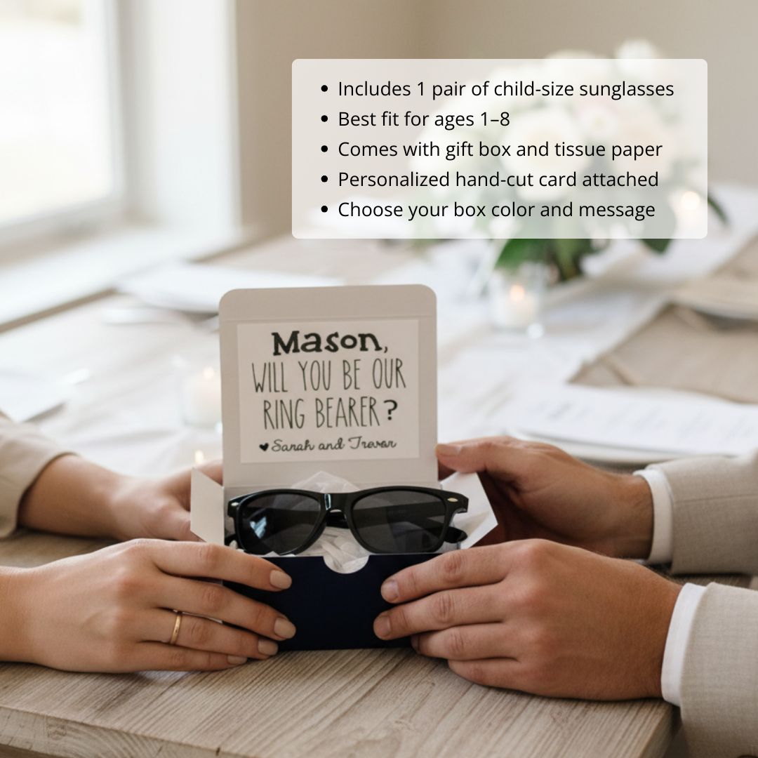 Child-size black sunglasses displayed in cream gift box with personalized hand-cut card reading "Will you be our ring bearer?" with sample names Mason, Sarah and Traven