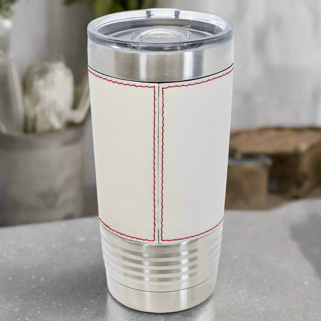 Stainless steel tumbler with white leather-like sleeve and red stitching on a white background