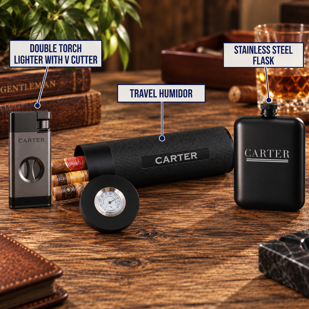 A lifestyle product display on a wooden table showing a black cylindrical travel humidor with a round lid, a black double torch lighter with a V-cutter, and a black stainless steel flask, all branded CARTER. The scene is styled with cigars, leather accessories, and an amber drink in a glass, with text callouts identifying each item.