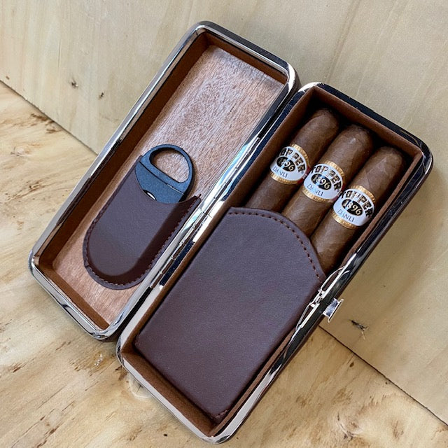 Cigar case with three cigars and a cutter on a wooden surface