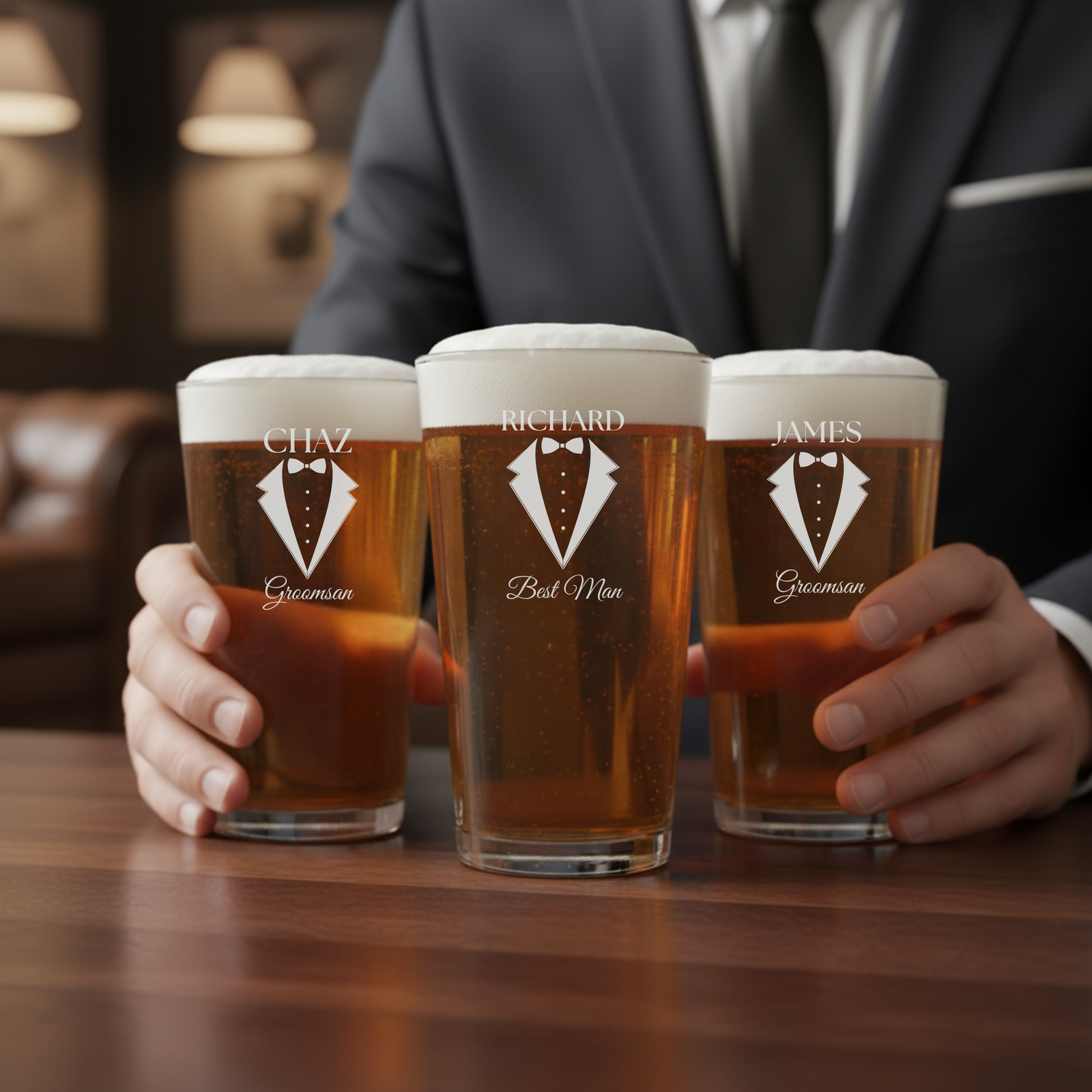 Three pint glasses filled with beer, personalized with sample names "Chaz," "Richard," and "James," each engraved with tuxedo design and roles "Groomsman" and "Best Man