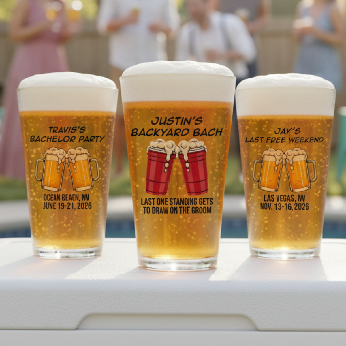 Three pint glasses filled with beer, each personalized with sample event details: left glass reads "Travis's Bachelor Party Ocean Beach NV June 19-21 2026" with beer mug graphics, center glass reads "Justin's Backyard Bach Last One Standing Gets To Draw On The Groom" with red keg graphics, right glass reads "Jay's Last Free Weekend Las Vegas NV Nov 13-16 2026" with beer mug graphics.