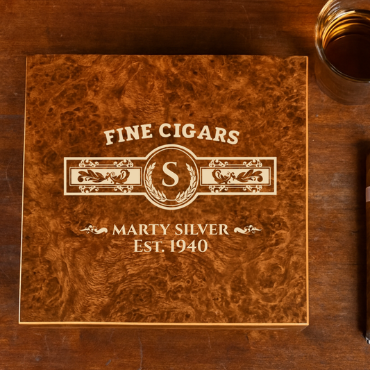 Wooden cigar humidor lid engraved with "FINE CIGARS," decorative wreath monogram with sample initial "S," and personalized text "MARTY SILVER EST. 1940