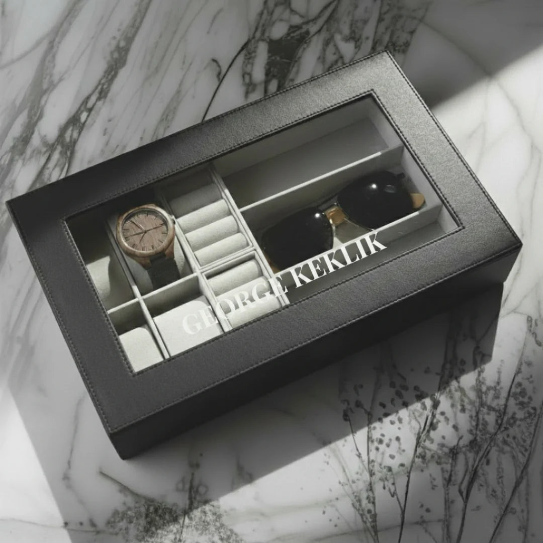 Gray jewelry box with watch, earrings, and other items on a marble surface