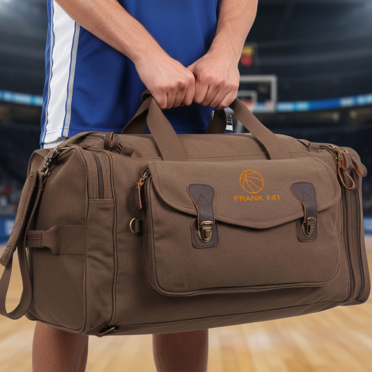 Groomsman carrying the brown canvas basketball duffle bag by its leather handles on a basketball court, showing its roomy weekender size.