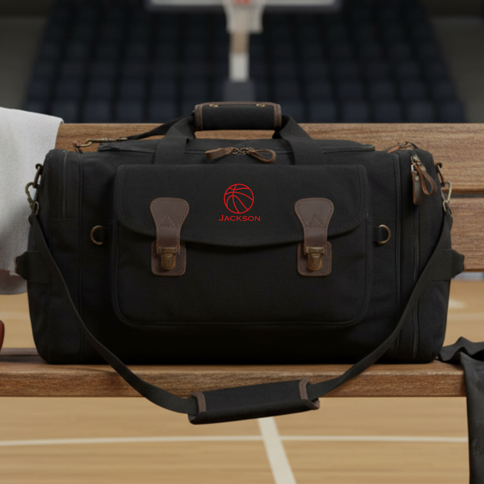 Black canvas basketball duffle bag with brass hardware and leather accents on a basketball court, a personalized groomsmen gift option.