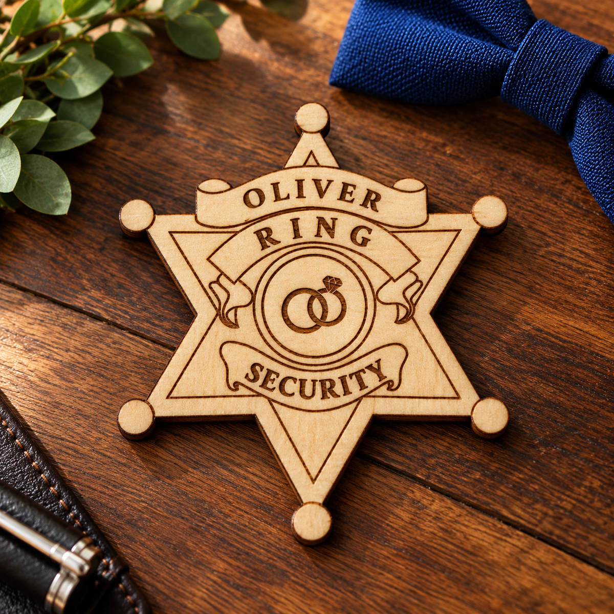 Personalized ring security badge, a wood sheriff star engraved with the name OLIVER above RING SECURITY, lying on white wedding linen