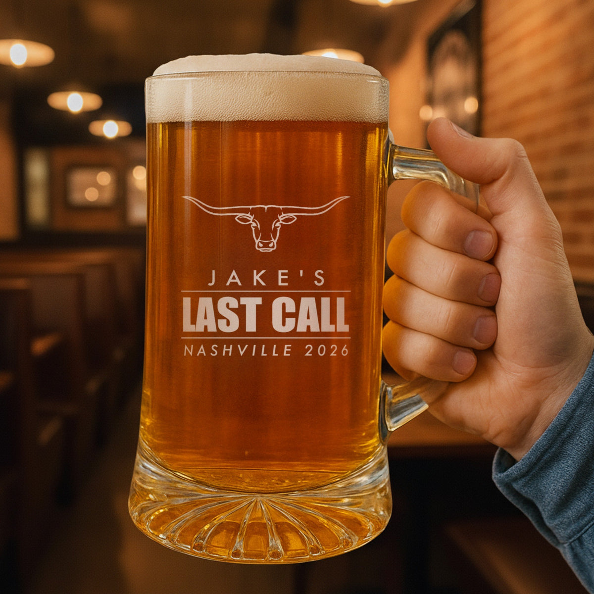 Hand holding a personalized bachelor party beer stein in a pub, engraved with a longhorn and Jake's Last Call, Nashville 2026