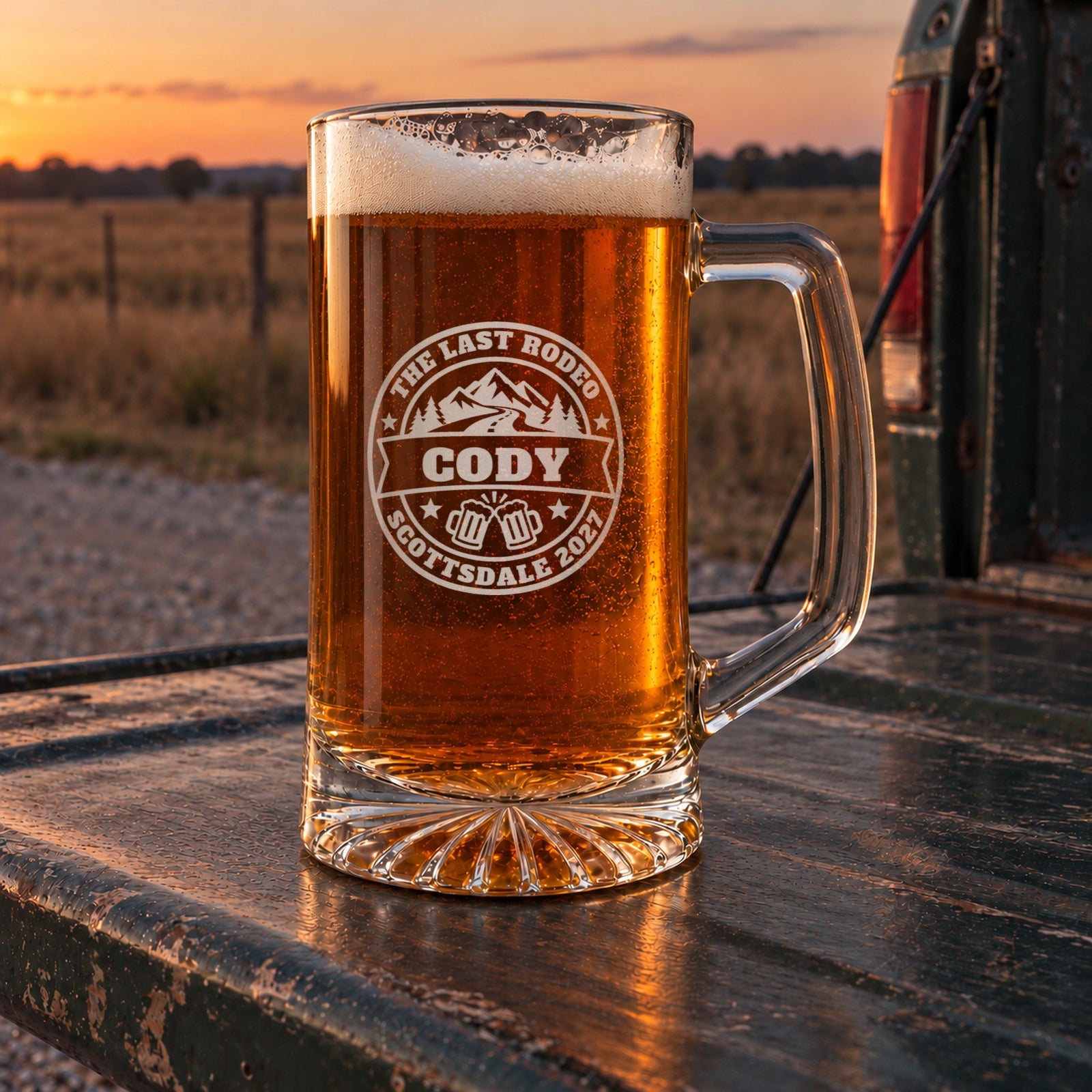 Bachelor party beer stein on a pickup tailgate at sunset in open country, engraved with the mountain badge, The Last Rodeo, Cody and Scottsdale 2027