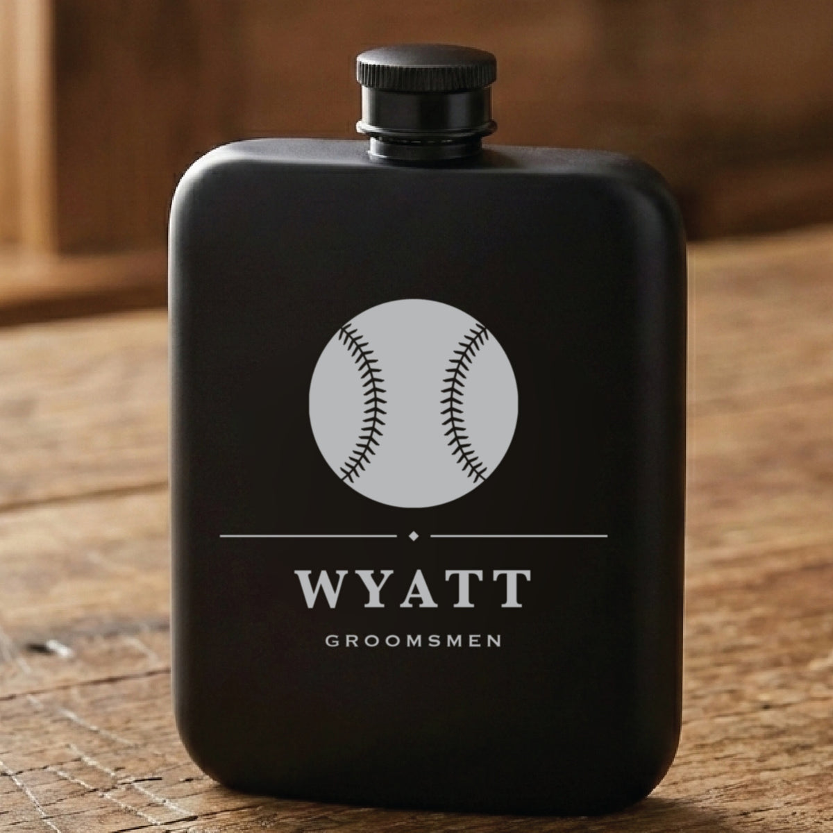 Matte black baseball groomsmen flask laser engraved with a stitched baseball, the name Wyatt and the word Groomsmen beneath it.