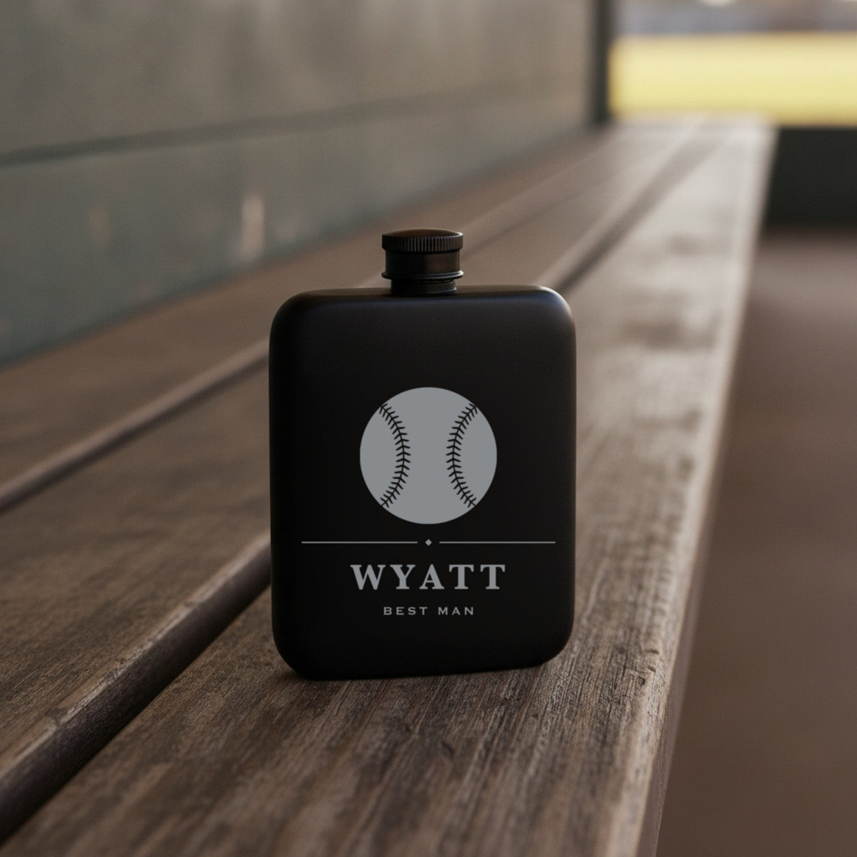 Personalized baseball flask engraved Best Man standing on the worn wooden bench of a dugout with the sunlit field behind it.