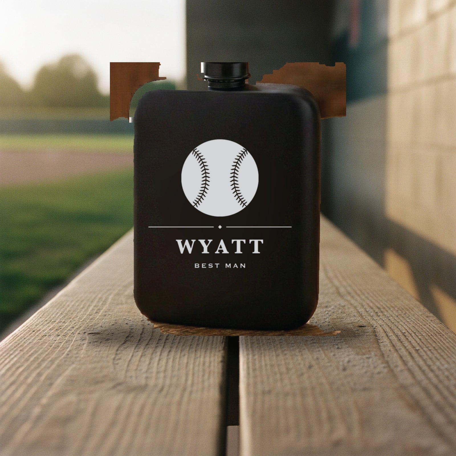 Personalized baseball flask engraved Best Man standing on the worn wooden bench of a dugout with the sunlit field behind it.