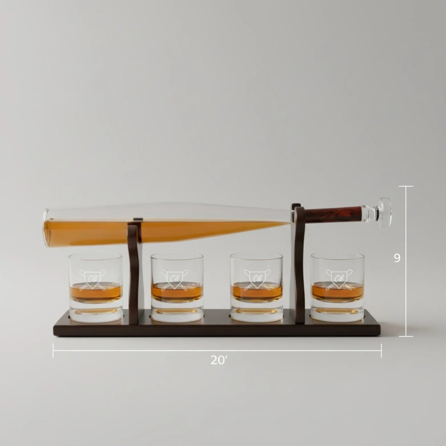 Baseball bat decanter set with four whiskey glasses featuring engraved monogram bases, displayed on dark wood stand with dimensions marked
