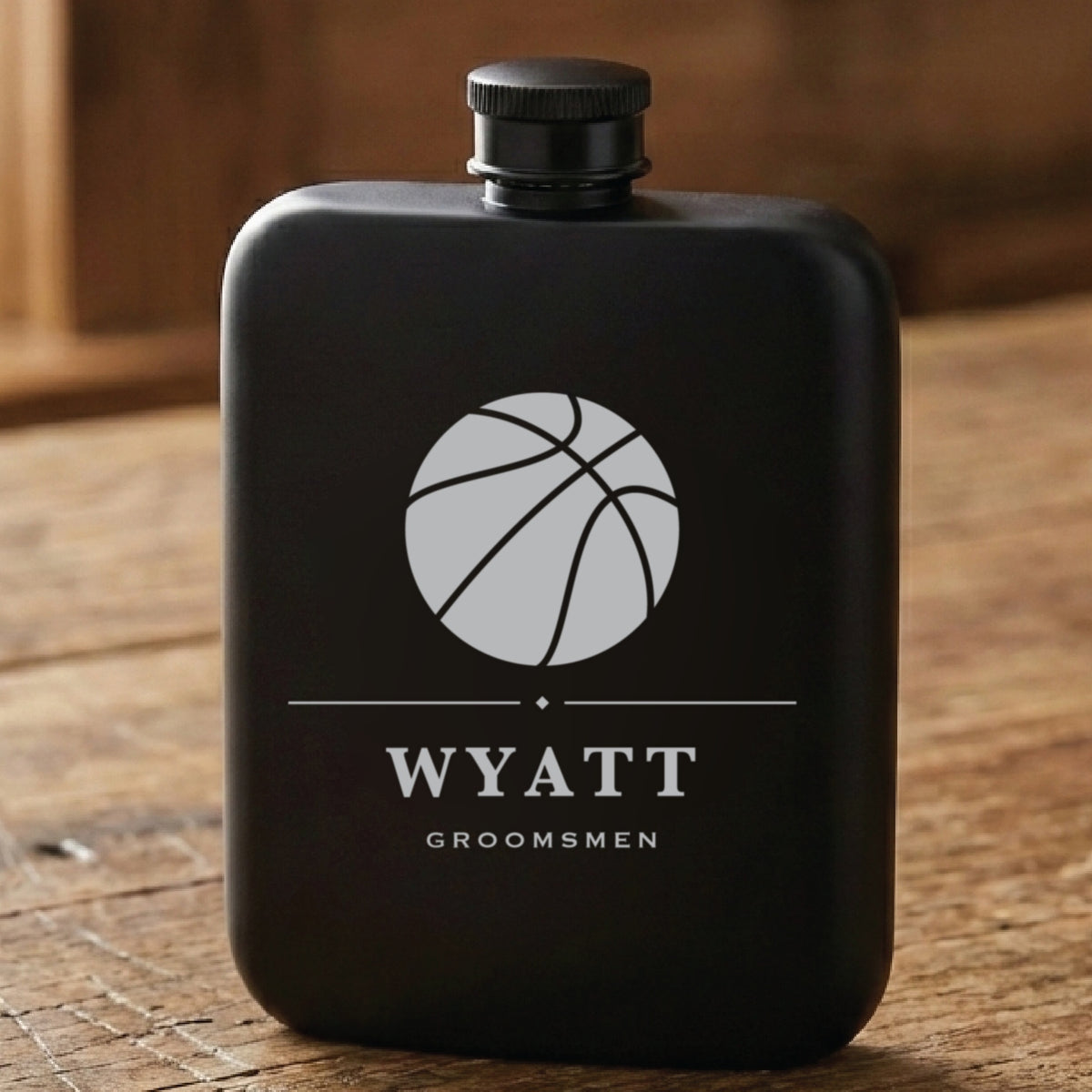 Matte black basketball groomsmen flask laser engraved with a seamed basketball, the name Wyatt and the word Groomsmen beneath it.
