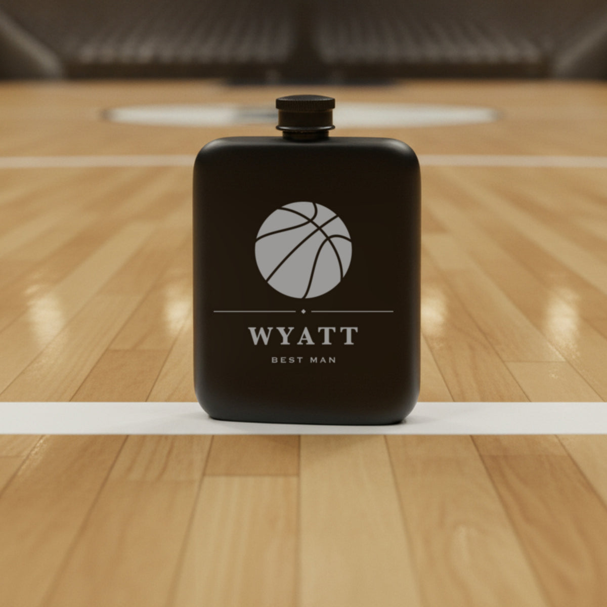 Personalized basketball flask engraved Best Man standing on a polished hardwood court with the empty gym seating behind it.