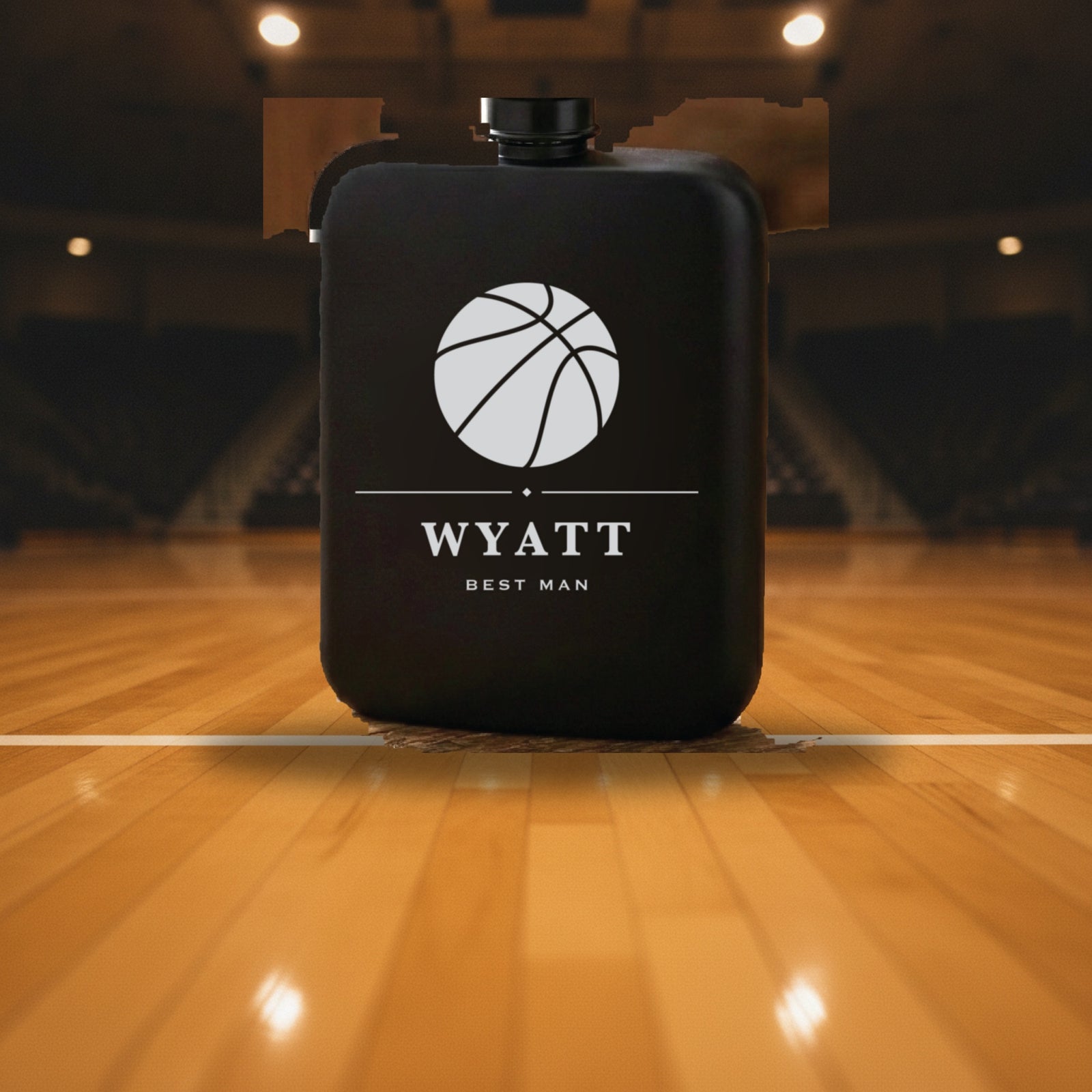 Personalized basketball flask engraved Best Man standing on a polished hardwood court with the empty gym seating behind it.