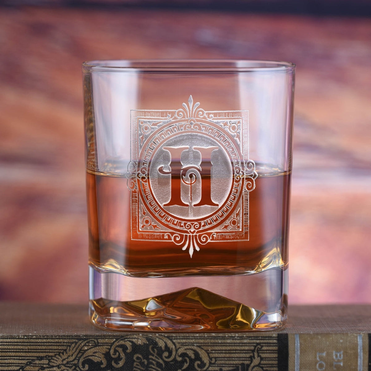 Real photo of the Bormioli personalized whiskey rocks glass with bourbon, sand-carved with an ornate square frame and the initial H