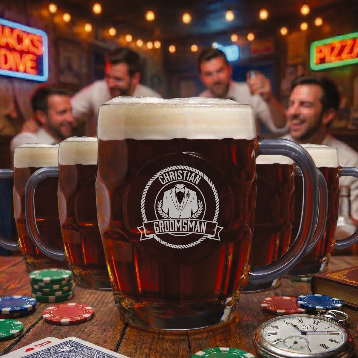 Beer mugs filled with dark beer and foam, engraved with sample design "Christian Groomsman" featuring tuxedo and laurel wreath motif, displayed on bar table with poker chips and watch.
