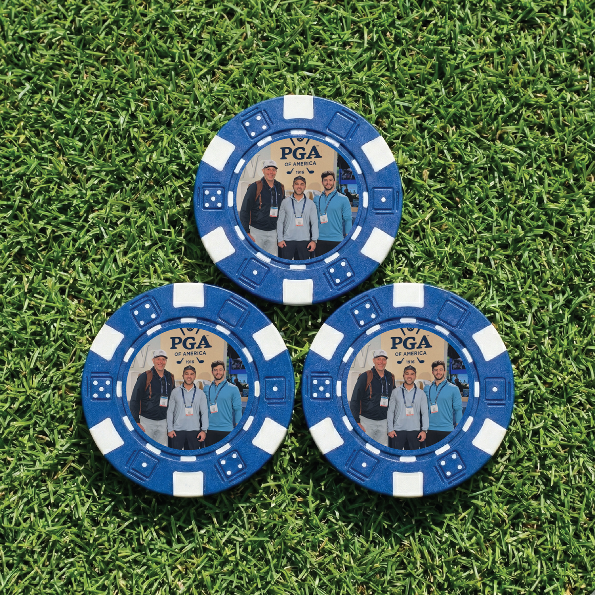 Three blue golf poker chips with PGA of America branding on a grass background