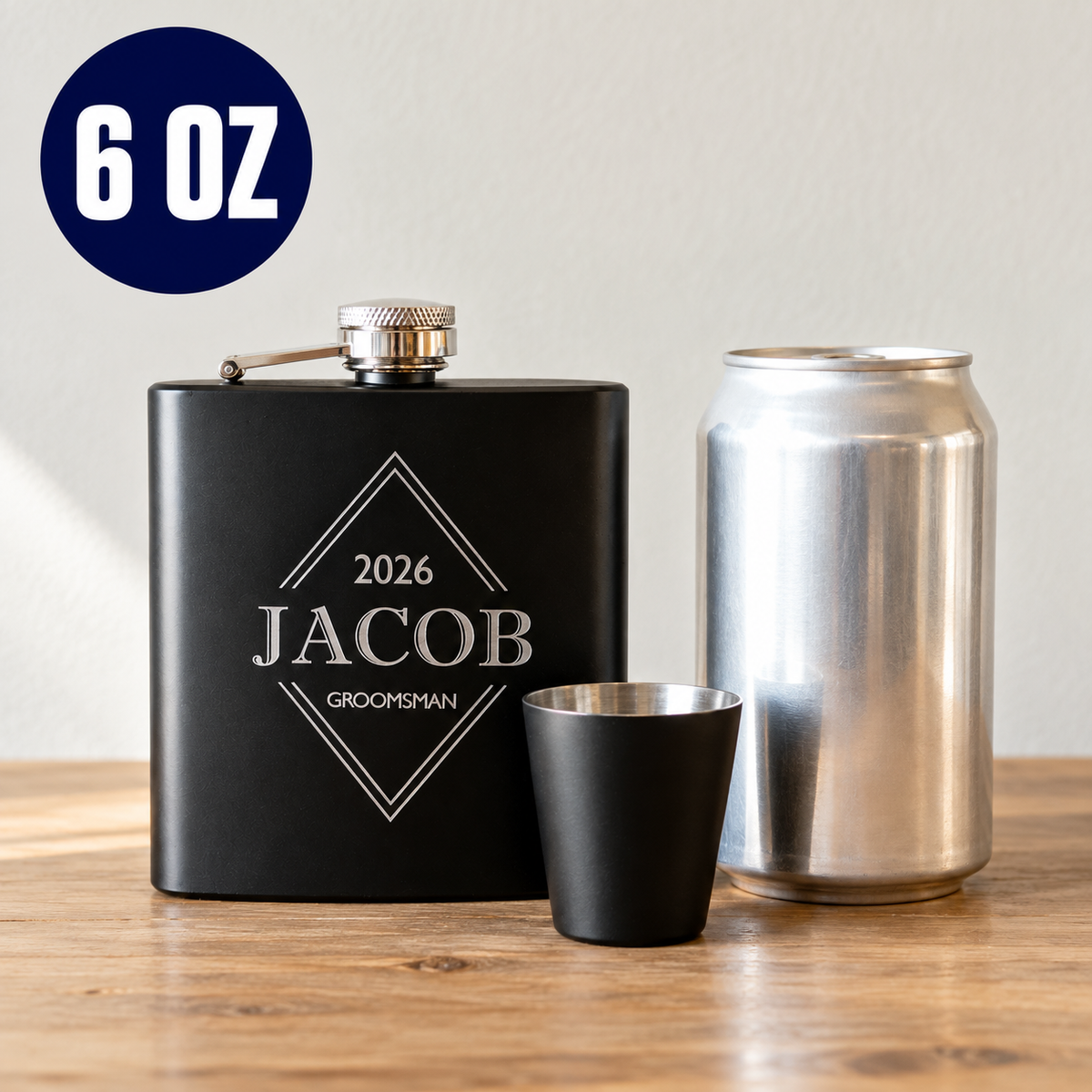Sharp Shooters 6 oz matte black flask engraved JACOB and GROOMSMAN standing next to a plain 12 oz can and a black shot glass to show the size of the flask