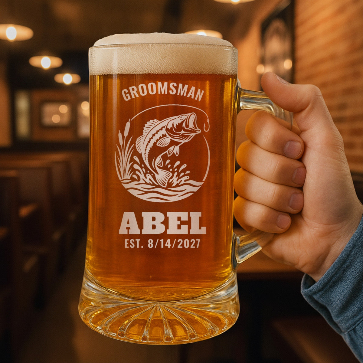 Hand holding the 25 oz personalized fishing beer stein in a pub, engraved with a leaping largemouth bass: Groomsman, Abel, Est. 8/14/2027